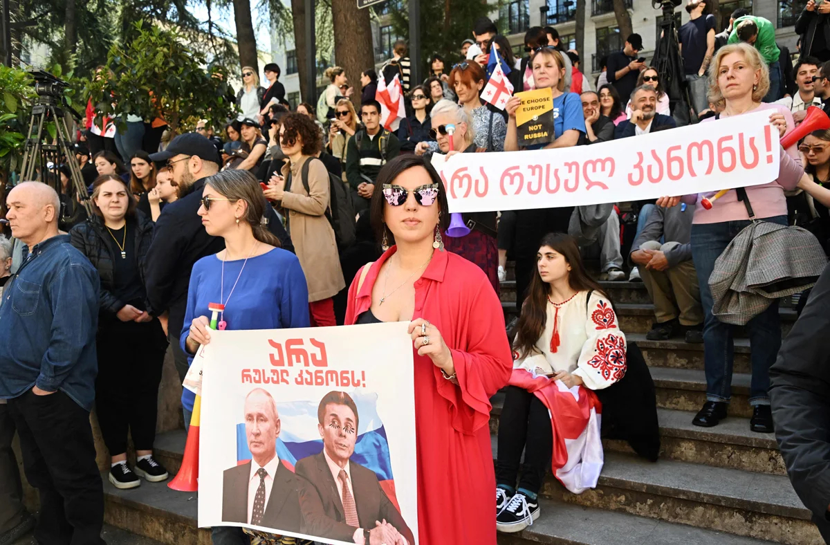 Участница митинга держит баннер с изображением Владимира Путина и Бидзины Иванишвили во время акции у парламента в Тбилиси, 16 апреля 2024 года. Фото: Vano Shlamov / AFP / Scanpix / LETA