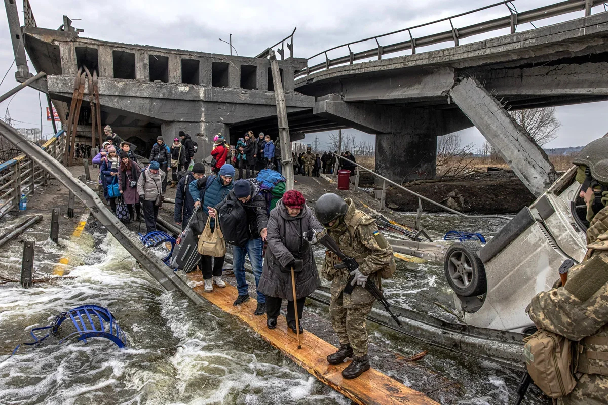 People cross the destroyed bridge as they flee from the frontline town of Irpin , 7 March 2022. Roman Pilipey / EPA-EFE