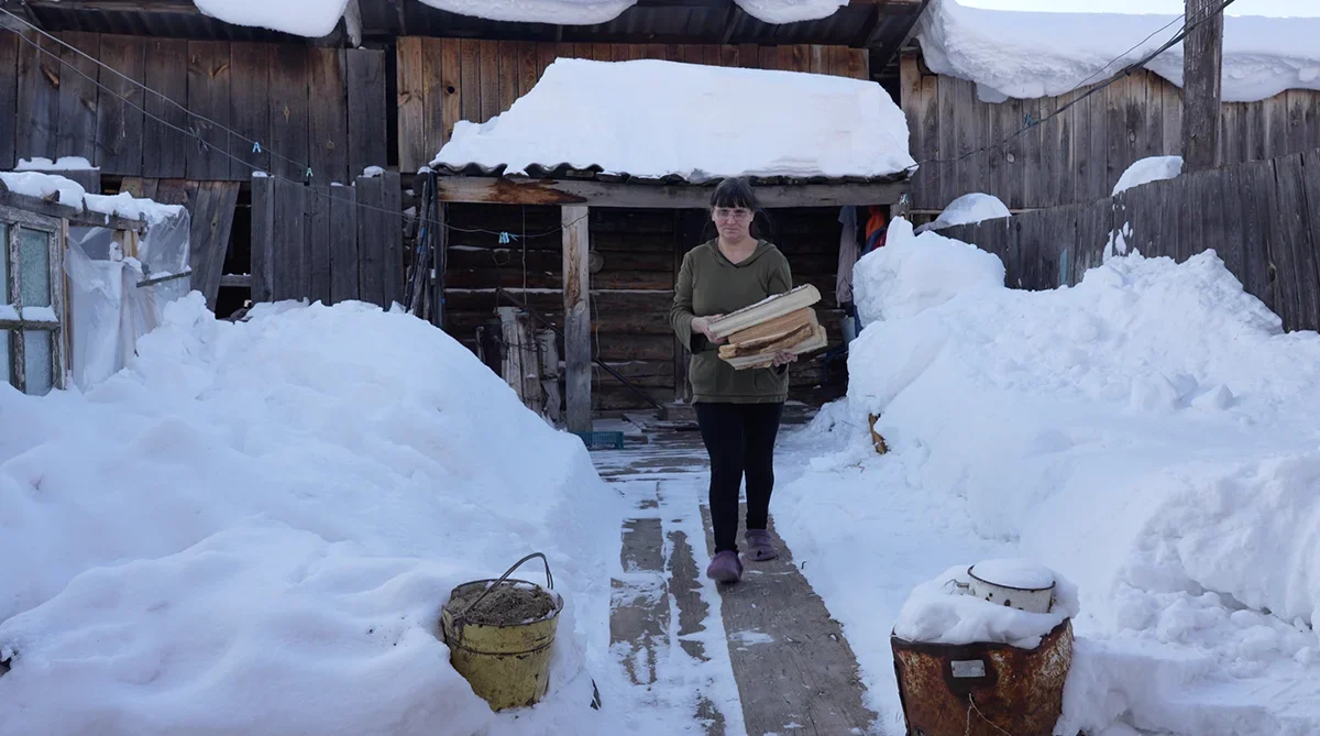 Natalia, the mother of a mobilised soldier, with firewood that her neighbour brings her. A shot from the film “Firewood for the mobilised”