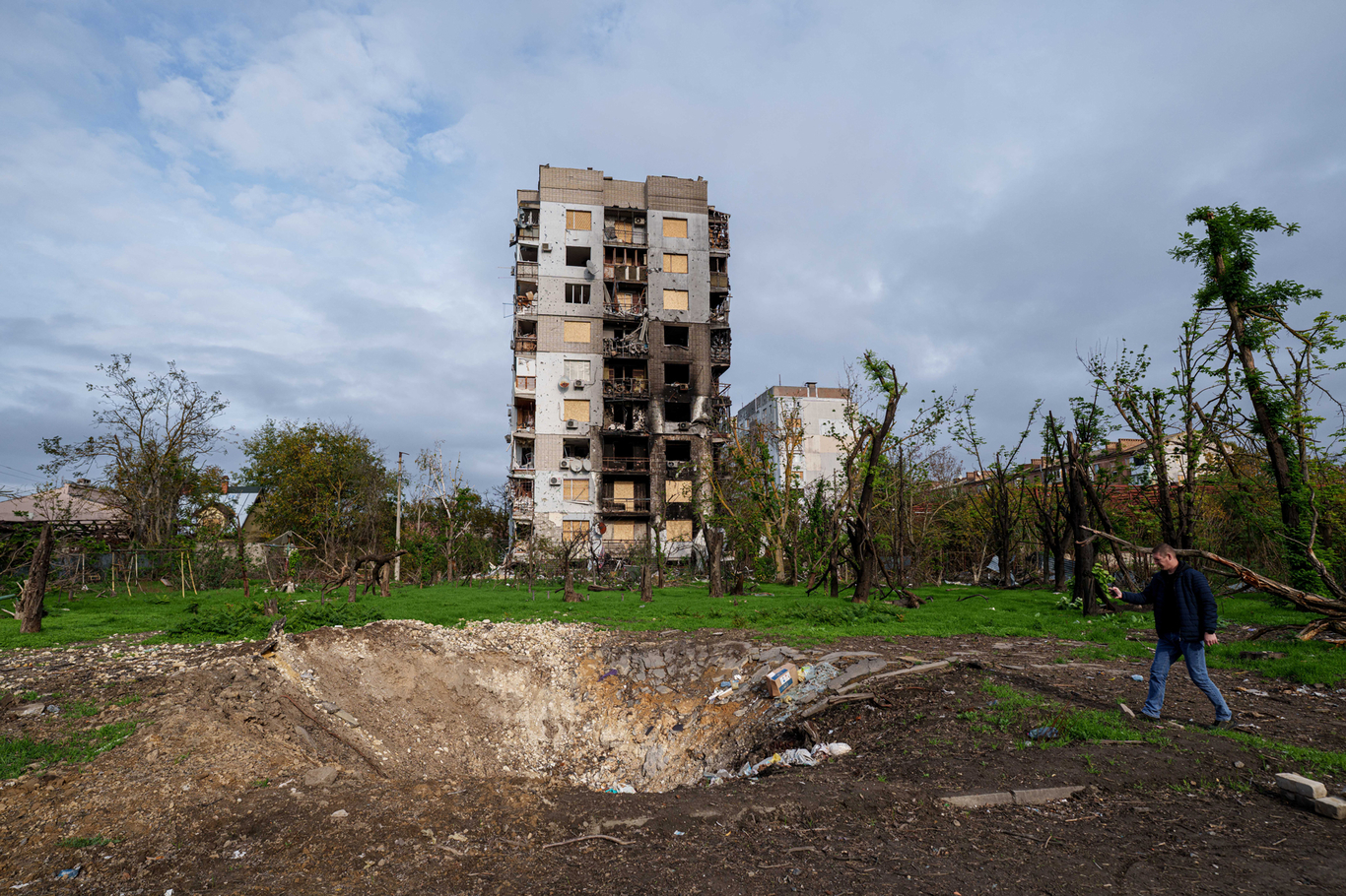 Мужчина фотографирует воронку и жилые дома, поврежденные в результате авиаударов. Херсон, Украина. 28 октября 2026 года. Фото: Evgeniy Maloletka / AP / Scanpix / LETA