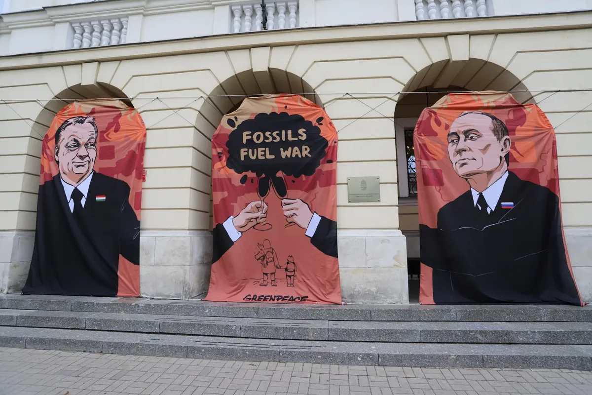 Баннер с изображением Виктора Орбана и Владимира Путина и лозунгом «Ископаемые — топливо войны» во время акции Greenpeace с требованием бойкота российской нефти перед посольством Венгрии в Варшаве, 25 мая 2022 года. Фото: EPA-EFE