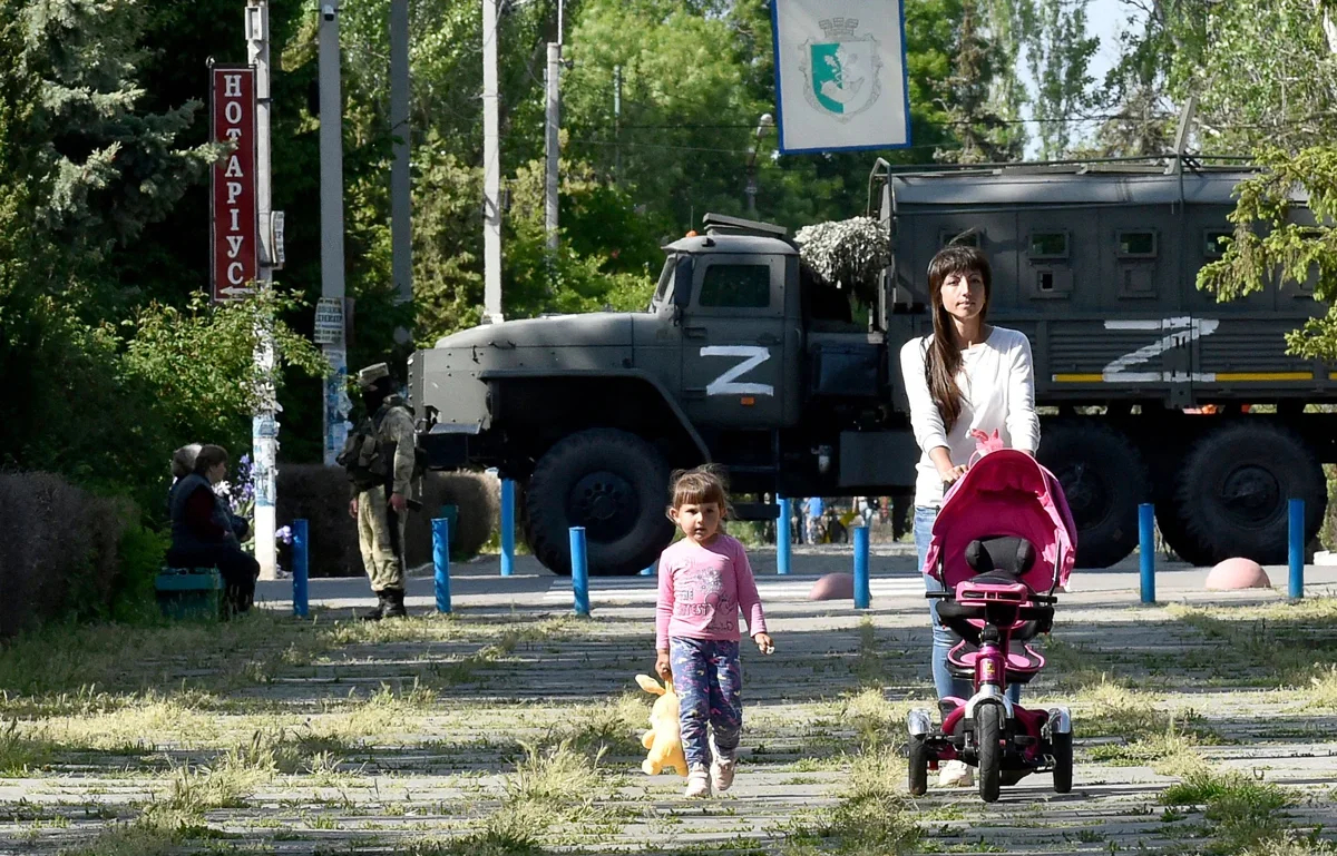 A woman and child pass Russian soldiers in Skadovsk, Zaporizhzhia region, Ukraine, 20 May 2022. Photo: Olga Maltseva / AFP / Scanpix / LETA