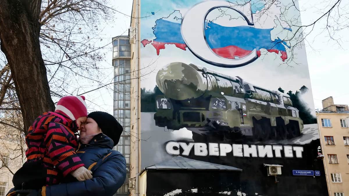 A woman carries her child past a Moscow building covered in a mural of a Russian intercontinental ballistic missile with the word “Sovereignty” written on it. Photo: EPA/YURI KOCHETKOV