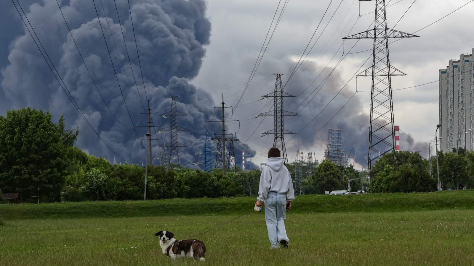 A dog walker watches as a pall of black smoke rises over Moscow following a Ukrainian airstrike, 18 June 2026. Photo: EPA