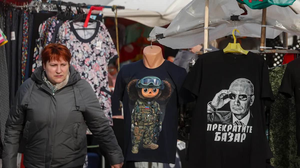 A woman walks past a stall selling “patriotic” shirts, including one with a portrait of Vladimir Putin and the slogan “Stop talking” in the Tula region town of Yefremov, Russia, 6 April 2023. Photo: EPA-EFE / MAXIM SHIPENKOV
