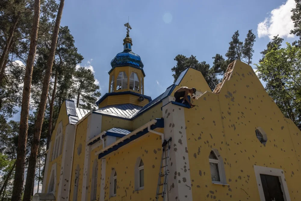 A man repairs a church damaged during Russian attacks in Irpin, Ukraine, 1 July 2022. Photo: Roman Pilipey / EPA-EFE