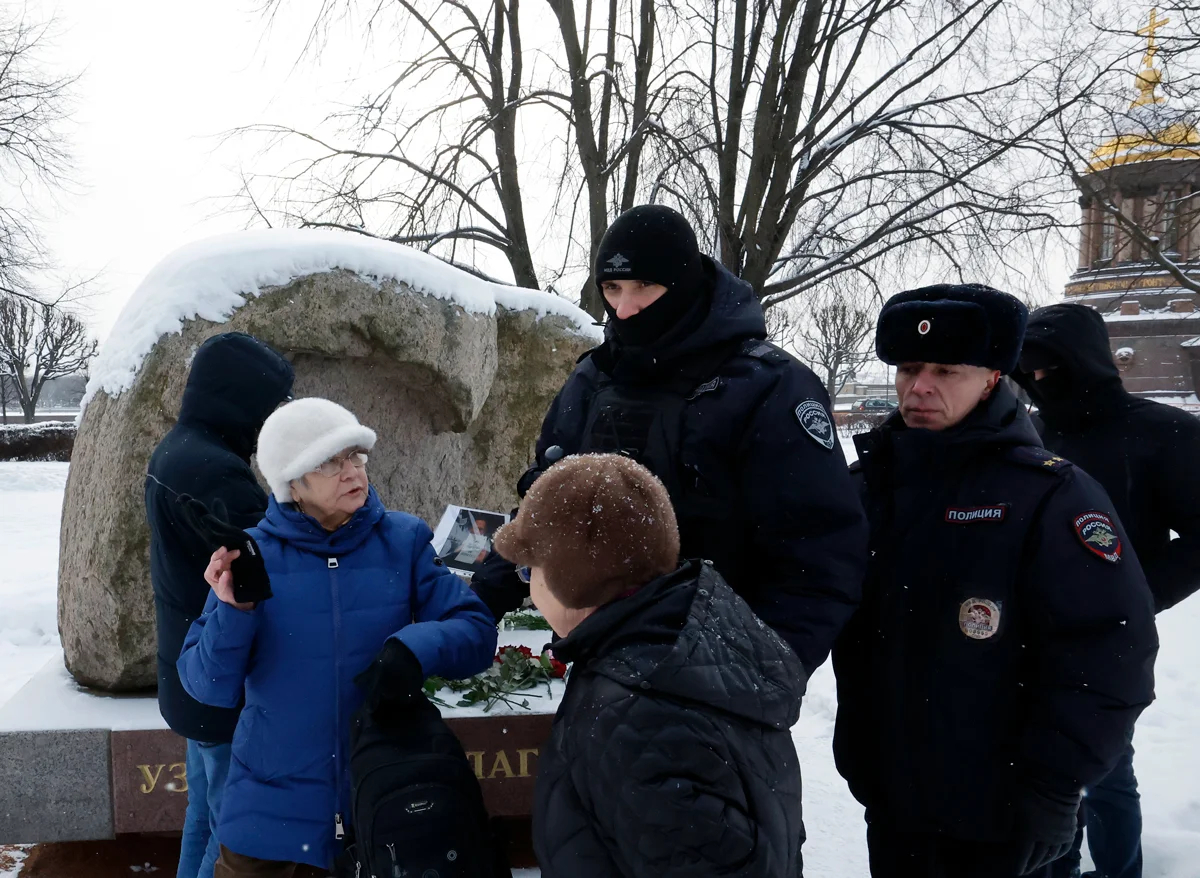 Полиция задерживает женщину за попытку разместить портрет Алексея Навального на мемориале политическим заключенным в Санкт-Петербурге, 16 февраля 2025 года. Фото: Анатолий Мальцев / EPA