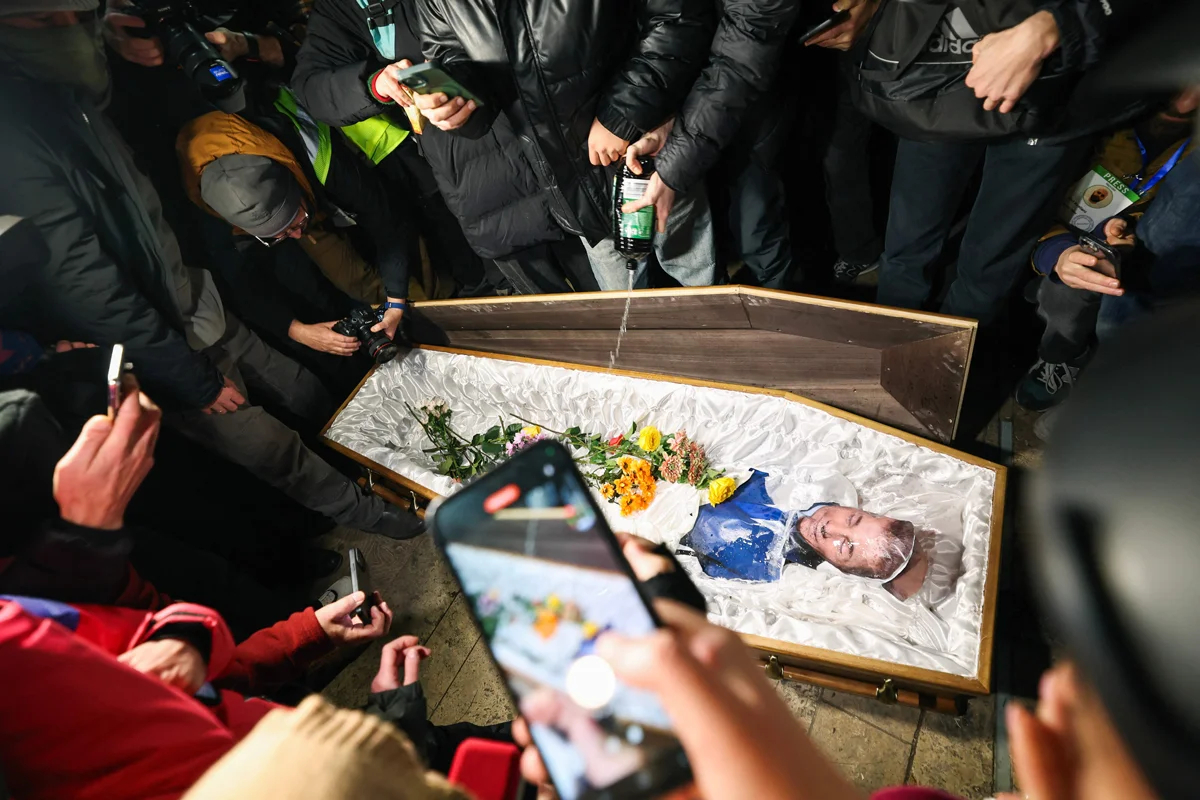 Демонстранты выливают горючую жидкость в гроб с изображением Бидзины Иванишвили на акции протеста в Тбилиси, 9 декабря 2024 года. Фото: Giorgi Arjevanidze / AFP / Scanpix / LETA