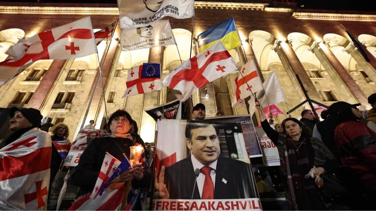 Протестующий держит плакат с изображением арестованного бывшего президента Грузии Михаила Саакашвили во время митинга, приуроченного к годовщине парламентских выборов, у здания парламента в Тбилиси, Грузия 26 октября 2025 года. Фото: Giorgi Arjevanidze / AFP / Scanpix / LETA