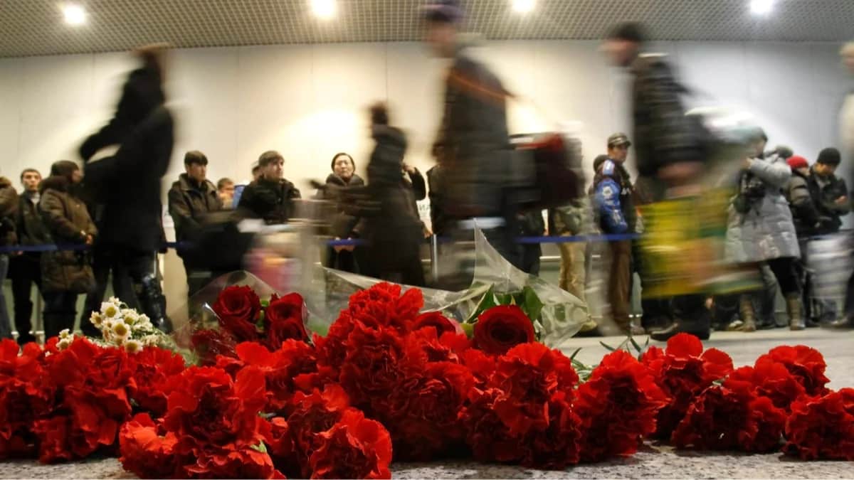 Пассажиры проходят мимо цветов, оставленных в память о погибших при взрыве в аэропорту Домодедово, 25 января 2011 года. Фото: Татьяна Макеева / Reuters / Scanpix / LETA