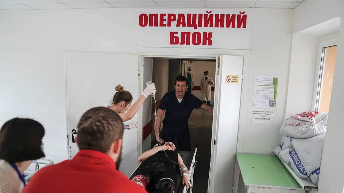 Фельдшер скорой помощи ввозит в операционную носилки с женщиной, пострадавшей в результате обстрела жилого района, Мариуполь, Украина, 1 марта 2022 года. Фото: Evgeniy Maloletka / AP photo / Scanpix / LETA