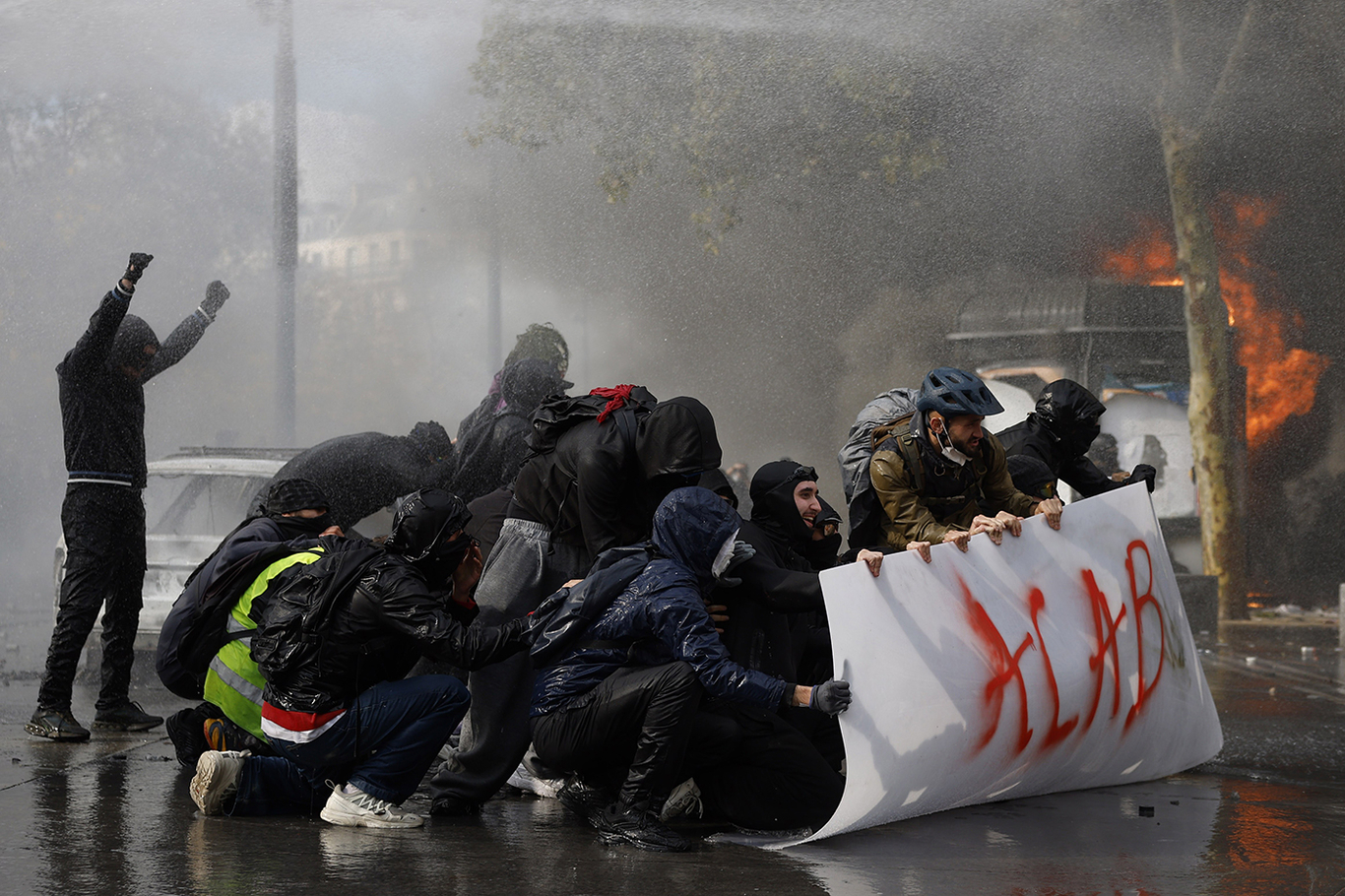 Протестующие прячутся за баннером с надписью «ACAB». Париж, Франция. 17 октября 2026 года. Фото: Yoan Valat / EPA
