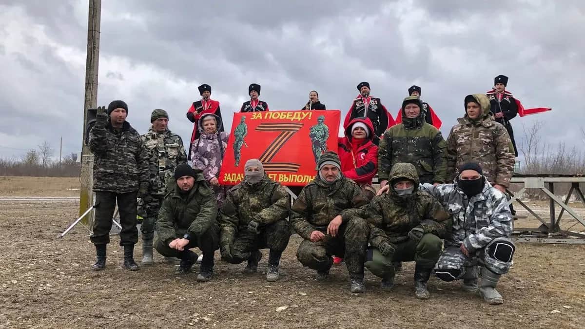 Anna Gromyko poses with Russian soldiers in an official Red Cross jacket and holding a banner saying "For victory. The mission will be completed." Photo: Anna Gromyko / Telegram