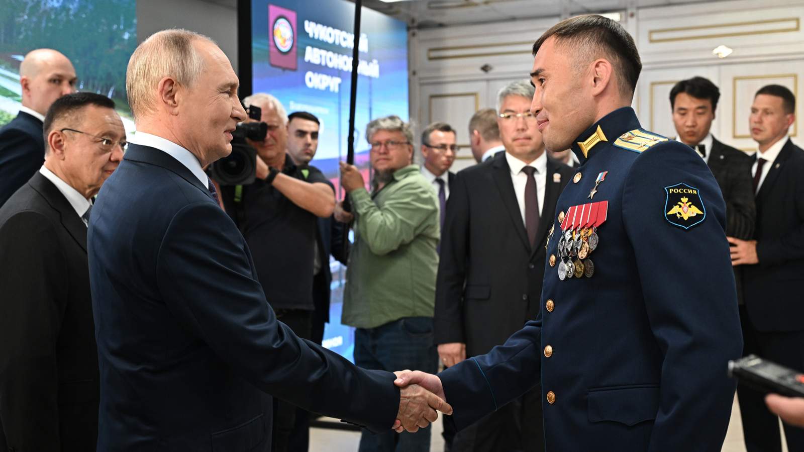 Владимир Путин жмет руку участнику программы «Время героев» подполковнику Дашибалу Мункожаргалову (в центре справа) во время посещения Бурятского государственного университета. Улан-Удэ, Республика Бурятия. 10 августа 2026 года. Фото: Кристина Соловьева / Спутник / Kremlin / EPA
